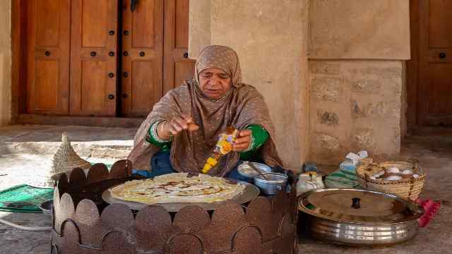 Exploring Captivating Traditions and Tours in Salalah 15 Omani-woman-in-traditional-dress-preparing-a-crispy-crepe-in-Oman-Travelstoyou