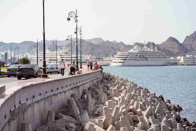 Next travel destination Oman affordable vacation Planning Service and Company 19 Western-tourists-in-Muscat's-Corniche-with-water-view-and-large-tourist-cruise-ship-in-the-harbour-Oman-by-Travelstoyou